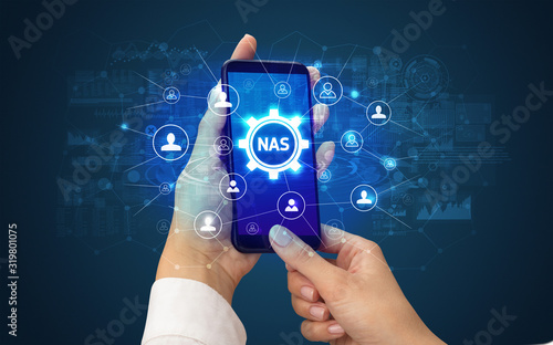 Female hand holding smartphone with NAS abbreviation, modern technology concept photo