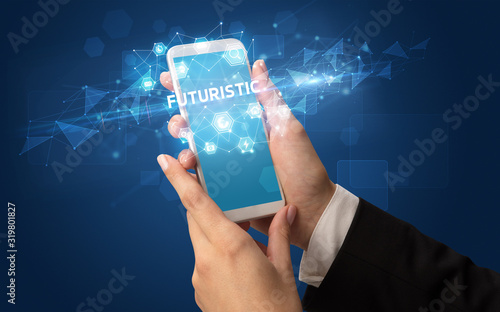 Female hand holding smartphone with FUTURISTIC inscription, modern technology concept