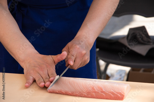 Japanese master chef preparing sashimi from fresh fish. Selective focus on man hands.