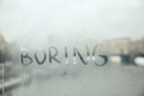  inscription  boring  on the misted glass of window. conceptual photo of boring mood in bad rainy weather