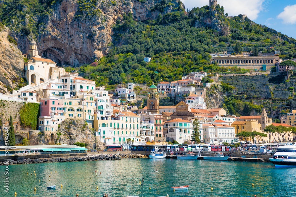 Beautiful Amalfi on hills leading down to coast, comfortable beaches and azure sea in Campania, Italy.