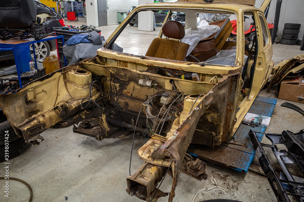 Fototapeta premium a garage there is a disassembled old car wreck to be restored