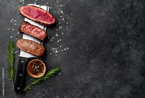 Three  pieces of meat grilled over a meat knife Three types of frying meat, rare, medium, well done. on stone background with copy space for your text