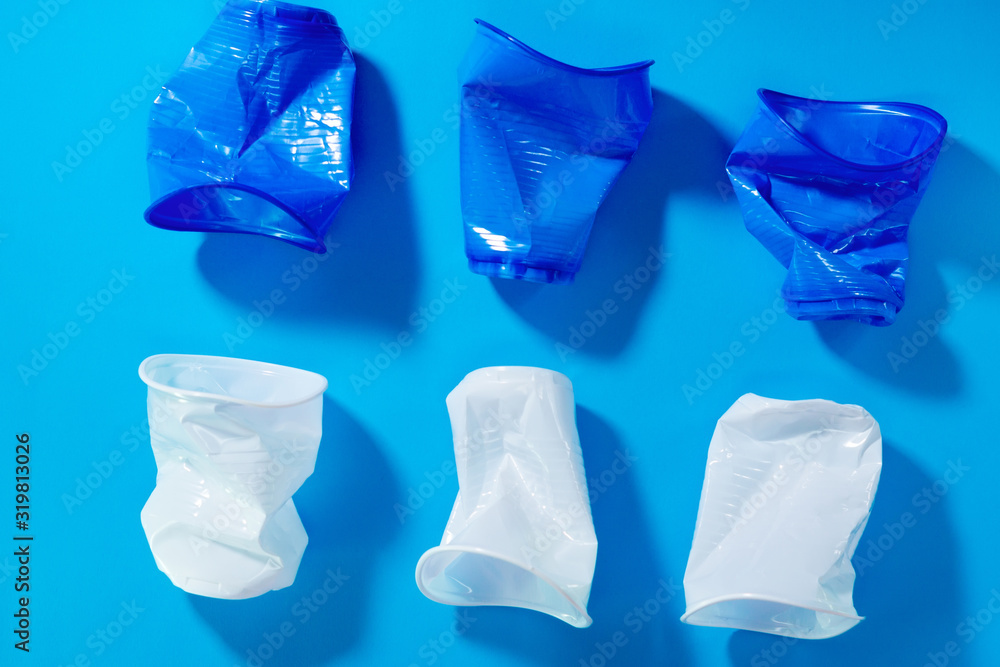 Naklejka premium disposable plastic cups on a blue background. the concept of abandoning plastic. the use of plastic