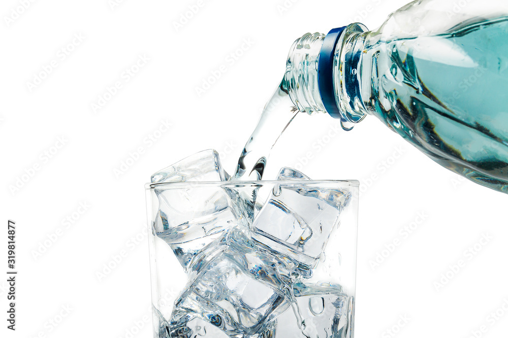 From the bottle water pours into a glass of ice, on a white background. From the bottle water pours into a glass of ice, on a white background.