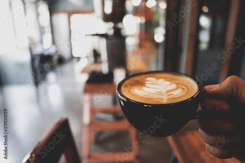 Hand holding Latte cup on blur coffee shop background
