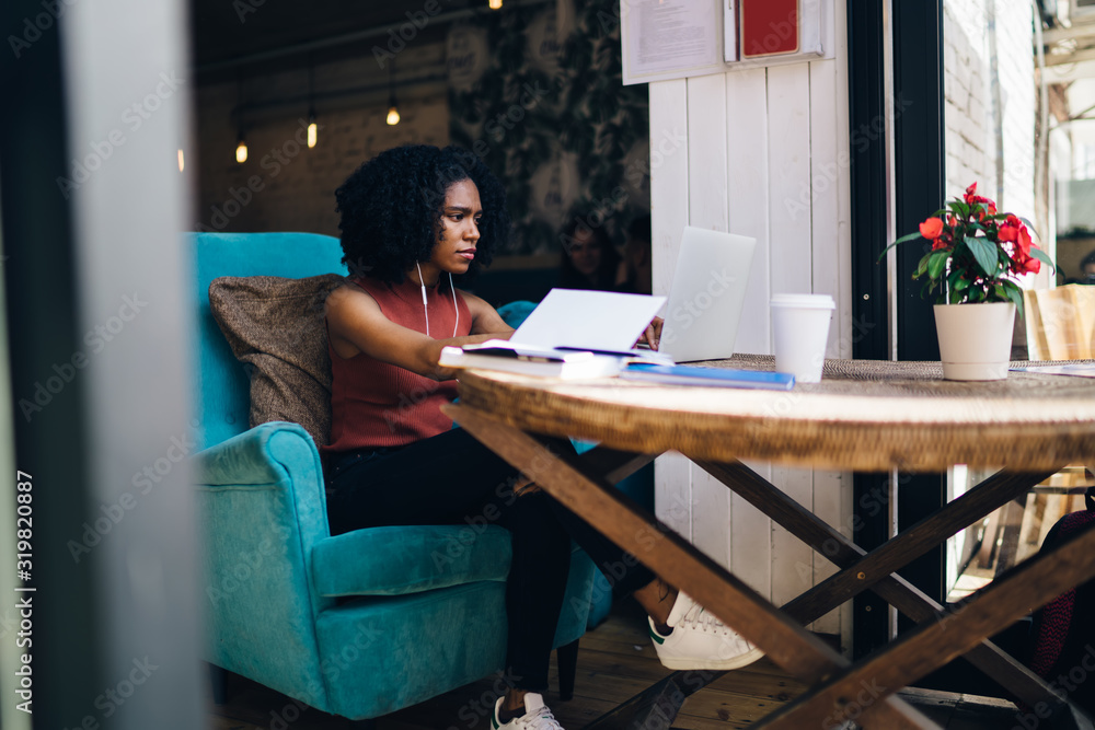 Fototapeta premium Concentrated black woman typing on laptop
