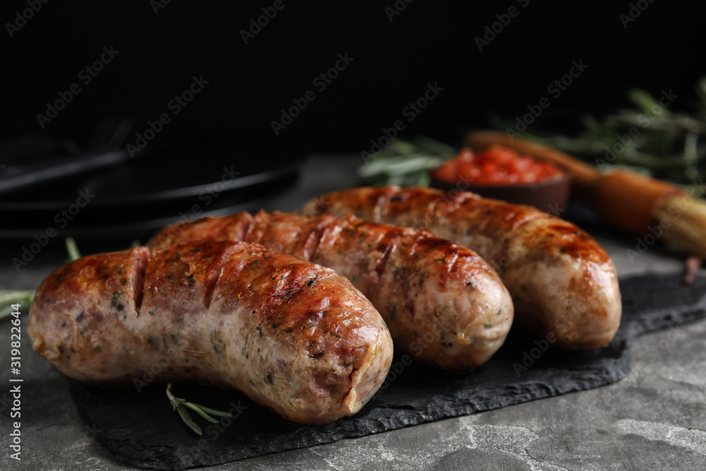 Tasty grilled sausages served on grey table Tasty grilled sausages served on grey table