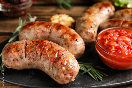 Tasty grilled sausages served on table, closeup
