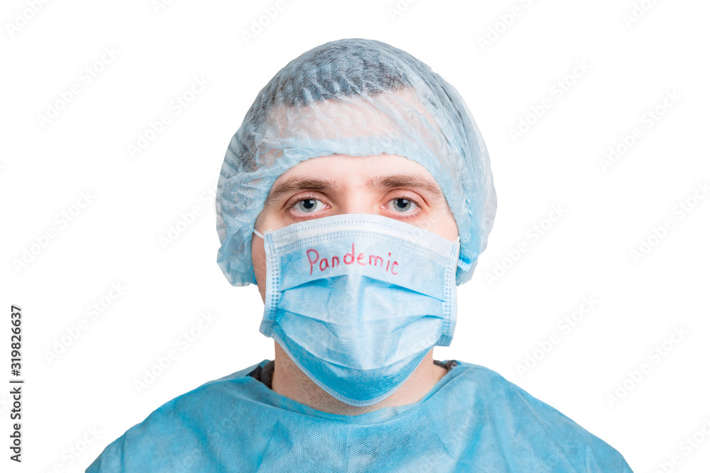 Portrait of young man wearing medical uniform and protective mask with pandemic word isolated on white background. Coronavirus and health care concept Portrait of young man wearing medical uniform and protective mask with pandemic word isolated on white background. Coronavirus and health care concept