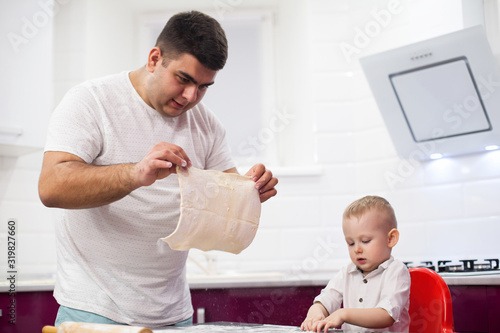 Father tossing pizza dough. Happy family in kitchen.