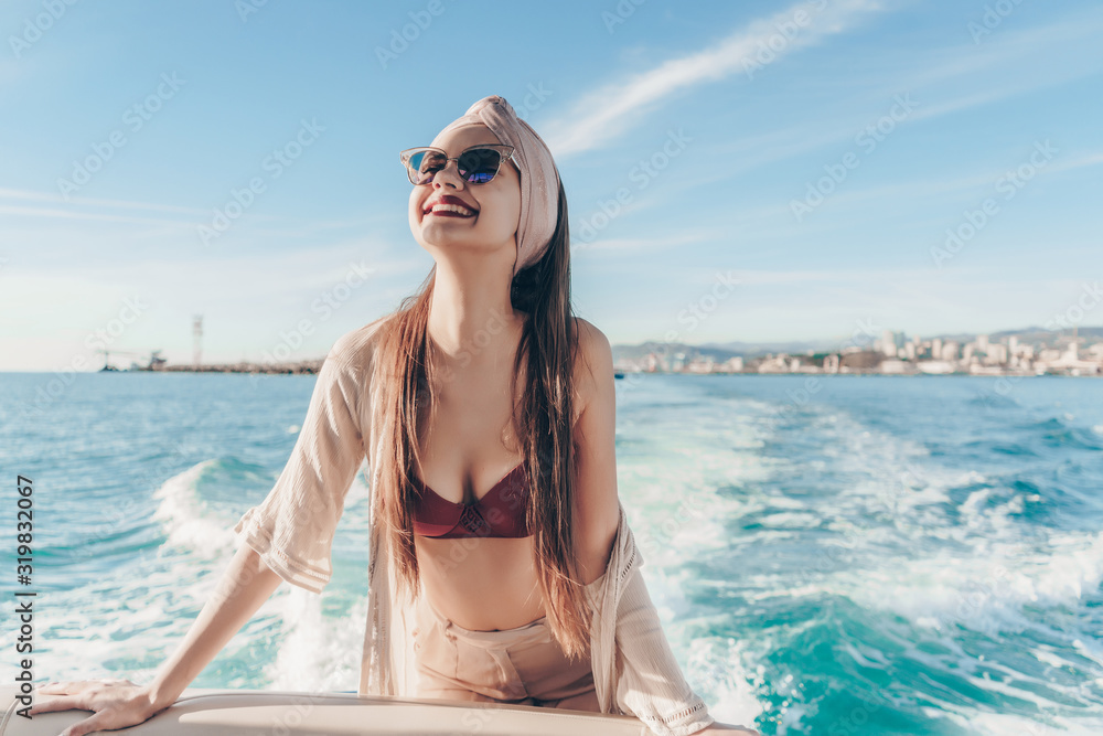a girl with a beautiful face and a scarf twisted in a turban on her head smiles joyfully on board a boat sailing on the waves