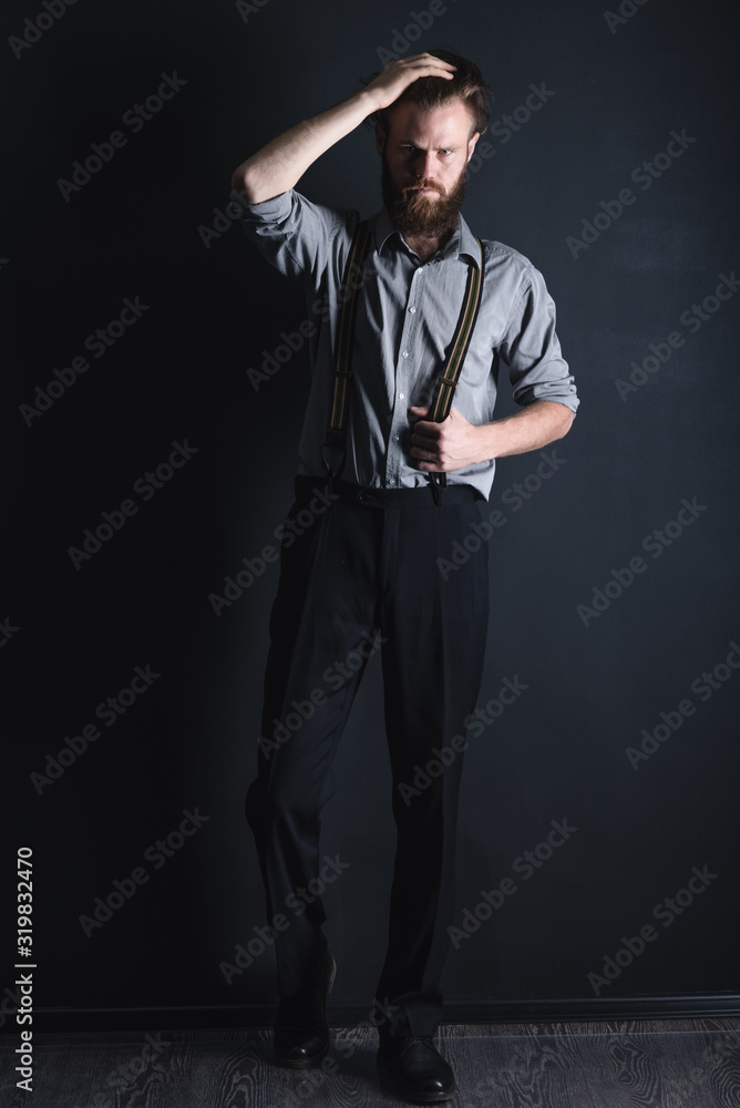 Young, handsome man with a beard posing on a black background in the studio. Young, handsome man with a beard posing on a black background in the studio.