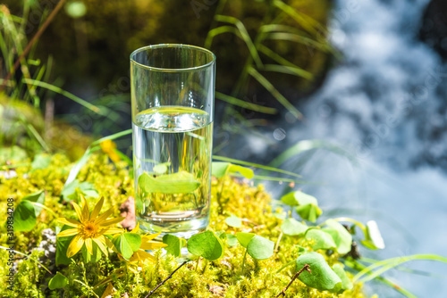 Natural water in a glass, against the background of nature and a mountain river, the concept of proper nutrition