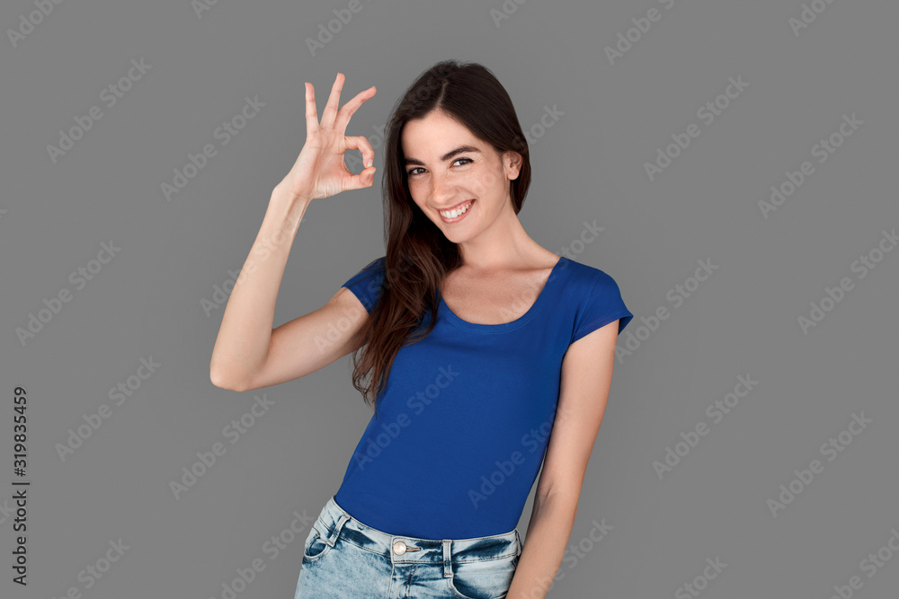 Young girl studio standing isolated on grey showing ok sign cheerful Young girl studio standing isolated on grey showing ok sign cheerful