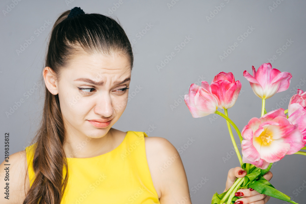girl with resentment and light squeamishness looks at a bouquet of tulips in her hand girl with resentment and light squeamishness looks at a bouquet of tulips in her hand