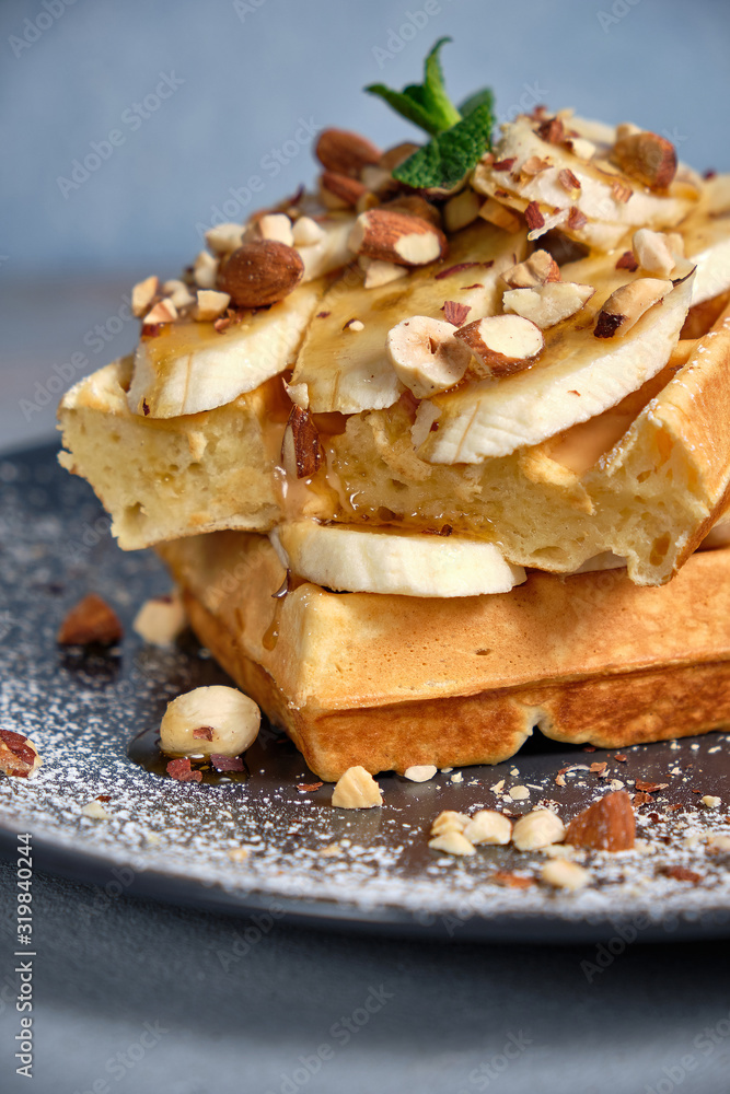 Sweet waffle with caramel and bananas sprinkled with hazelnuts and icing sugar Sweet waffle with caramel and bananas sprinkled with hazelnuts and icing sugar