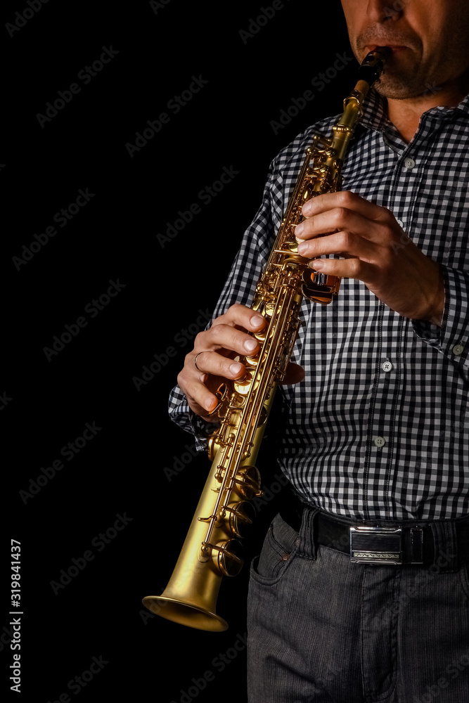 Naklejka premium soprano saxophone in hands on a black background