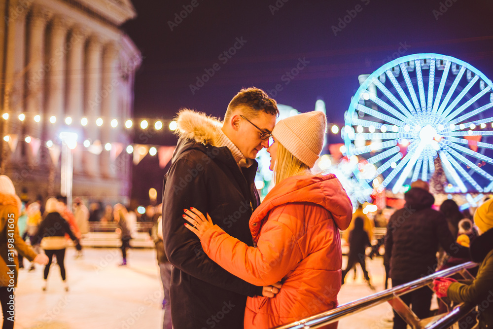 couple hugging in Saint Valentine's Day. Young romantic pair having fun outdoors in winter. St. Valentines Day at city ice rink. New Year holidays. active date ice skating on ice arena on Christmas