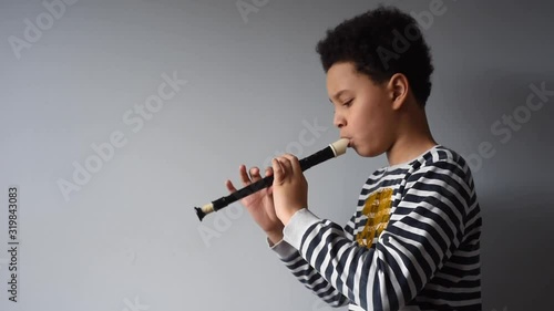 A young black african american teen playing the flute. A cute playful boy, having fun with his musical instrument. A young black boy learning how to play the flute.