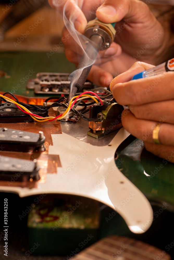 luthier soldering a guitar wire in his workshop