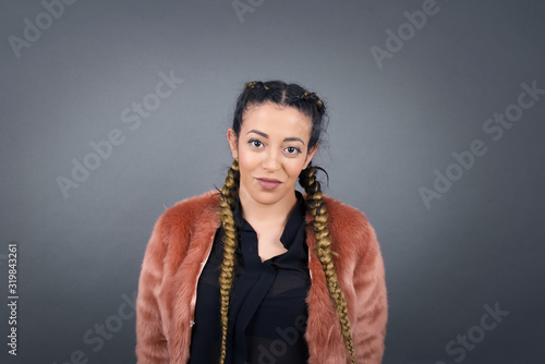 Close up studio shot of beautiful young mixed race woman model with curly dark hair looking at camera with charming cute smile while posing against white blank copy space wall for your content