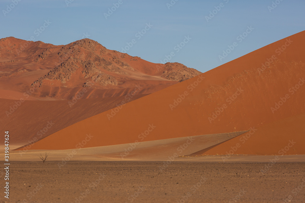 Beautiful landscape with red huge sand dunes at sunset in desert. Sossusvlei, Namib Naukluft National Park, Namibia. Stunning natural geometry without people