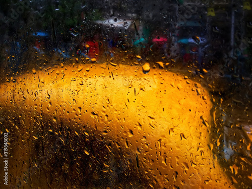 Raindrops falling on glass, abstract blurs - monsoon stock image of traditional yellow taxi of Kolkata formerly Calcutta city , West Bengal, India photo