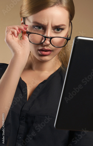 pretty girl taking off eye glasses and looking at the tablet with confused facial expression