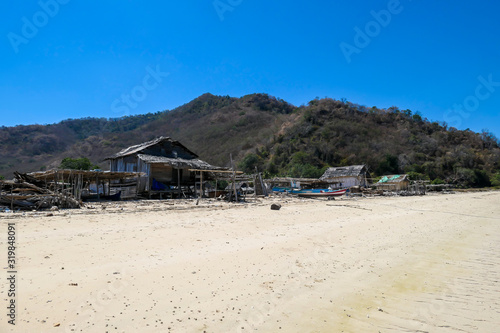 Fototapeta Naklejka Na Ścianę i Meble -  A distant view on a fishing cottage, located on a seashore of a small island next Flores, Indonesia. Houses located directly on the beach. Solitude and calmness. Simple construction