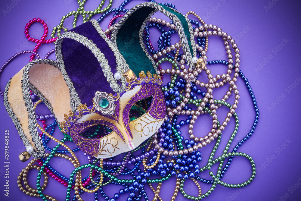 Fototapeta premium Festive mardi gras, venetian or carnivale mask on a purple background. Top view