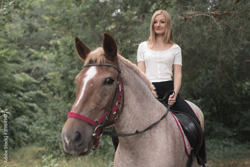 beautiful girl sitting on a horse in a forest.
