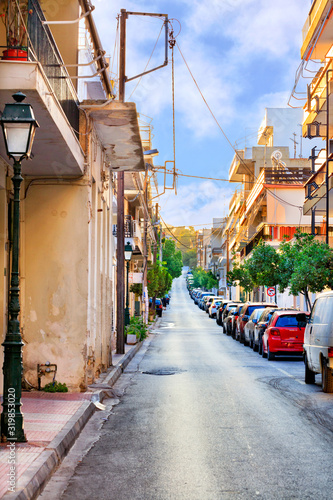 Deserted old narrow street of Loutraki in Greece in the early morning in the rays of the rising summer sun.