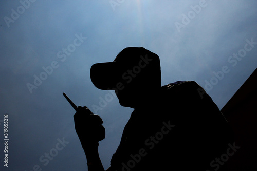 Fototapeta Low Angle View Of Security Guard With Walkie-Talkie Against Sky