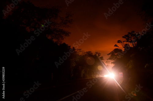Scenery of BR 101 highway at dusk. Atlantic Forest biome the banks of highway BR 101. A car with high headlights at the bottom of the scene.