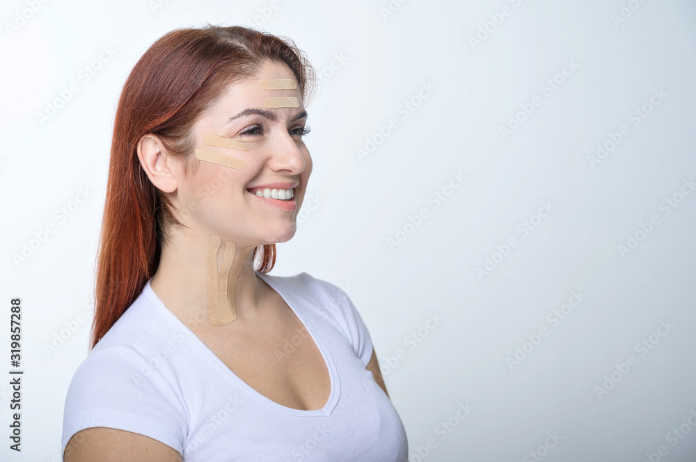Portrait of a redhead woman with tapes on skin color face for rejuvenation. An alternative way to fight wrinkles. Portrait of a redhead woman with tapes on skin color face for rejuvenation. An alternative way to fight wrinkles.
