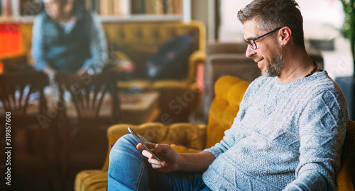 Middle-aged man working on mobile phone, sitting at the cafeteria, lifestyle concept photo