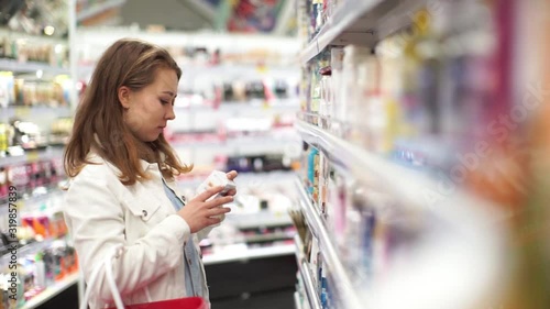 A beautiful woman buys cosmetics in a store. A girl in a cosmetics store. Beautiful woman shopping in a supermarket.The girl checks the composition of the product.