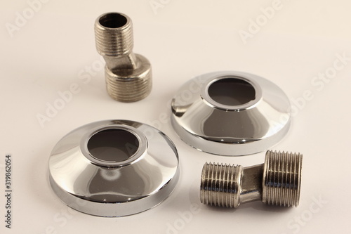 Eccentric adaptors with thread 1/2" - 3/4" and decorative chrome covers, faucet mounting kit in the bathroom wall, close up plumbing equipment on white background
