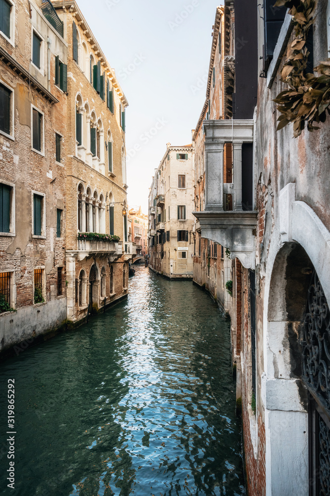 Colorful houses along narrow canal waters of Venice Italy