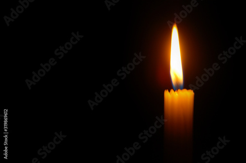 Bright orange glowing candle on black background