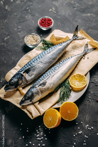 Mackerel with spices and herbs on a plate, fish still life on a dark background, assorted peppers, garlic, lemon, cherry tomatoes, dill