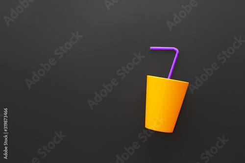 Yellow glass with a blue straw on a dark background