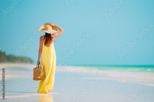 Young beautiful woman having fun on tropical seashore. Happy girl background the blue sky and turquoise water in the sea on caribbean island photo