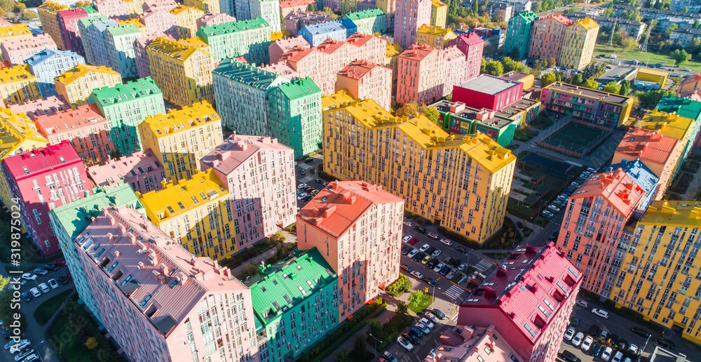 Fototapeta premium Urban landscape of colorful buildings. Aerial view of the colorful buildings in the European city in the morning sunlight. Cityscape with multicolored houses, cars on the street in Kiev, Ukraine.