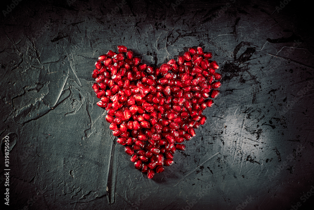 Heart shape pomegranate seeds on dark background Heart shape pomegranate seeds on dark background