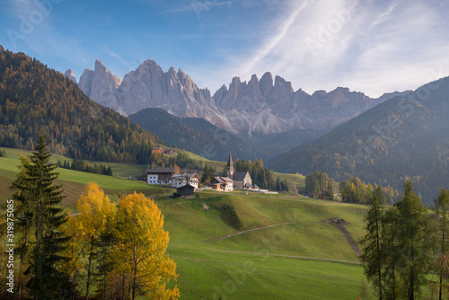 Church of Santa Magdalena in Val di Funes in South Tyrol in Italy during autumn day with trees in coloured foliage