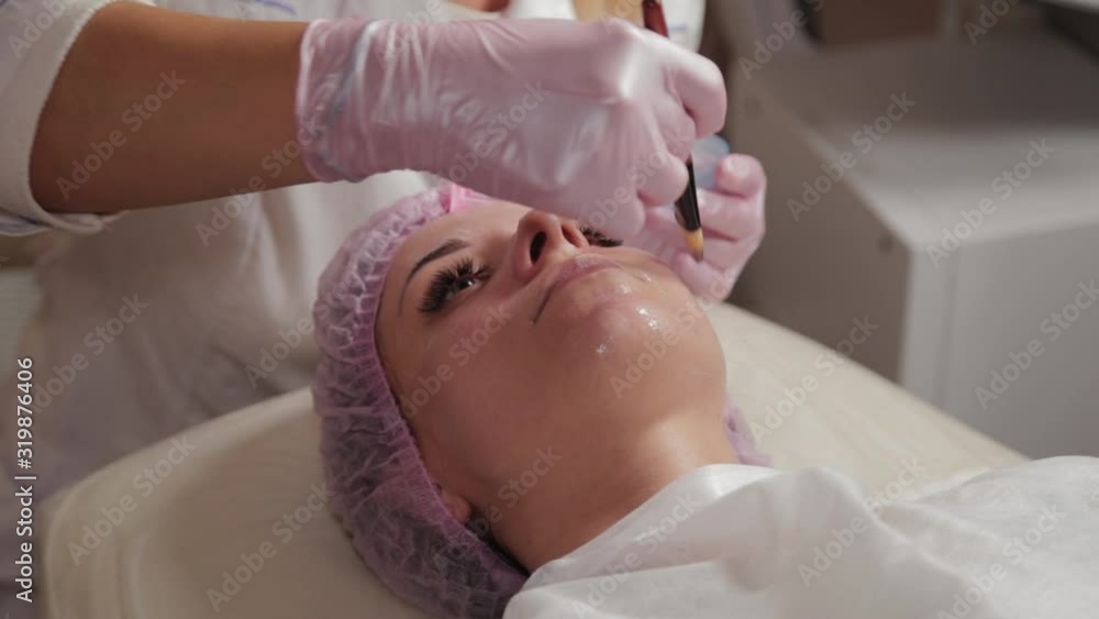 Professional beautician applying a mask on the face of the client with a brush. Professional beautician applying a mask on the face of the client with a brush.