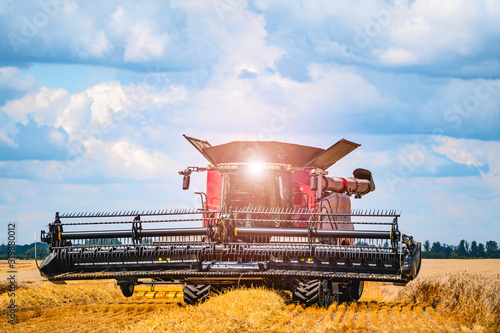 Special machine harvesting crop in fields, Agricultural technic in action. Ripe harvest concept. Crop panorama. Cereal or wheat gathering. Heavy machinery, blue sky above field © Vadim