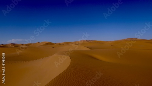 Sand dune with interesting shades and texture in Sahara with deep blue sky during midday sun, Morocco, Africa